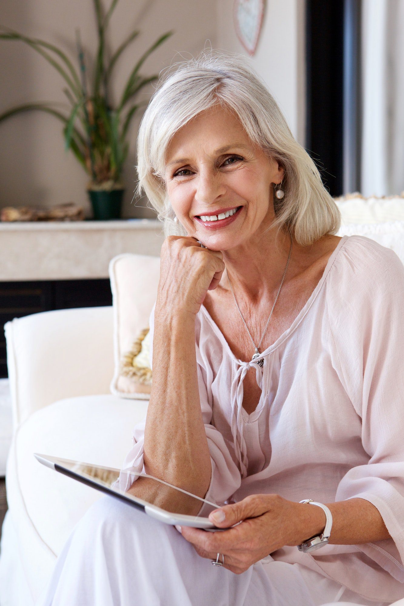 smiling older woman in living room with tablet